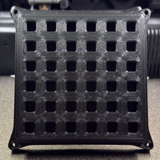 Finished black PPA-CF pool return grate with patterned face and four corner mounting points